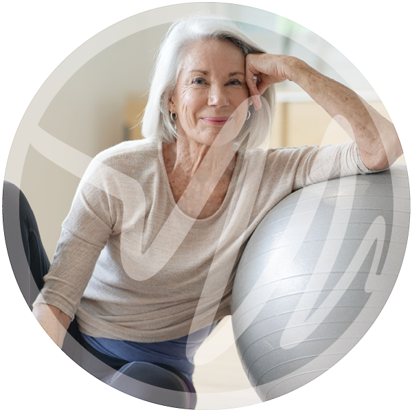 Active Senior Woman with Exercise Ball » PEMF Recovery Plus Elderly woman smiling confidently while resting on a stability ball during a wellness session.